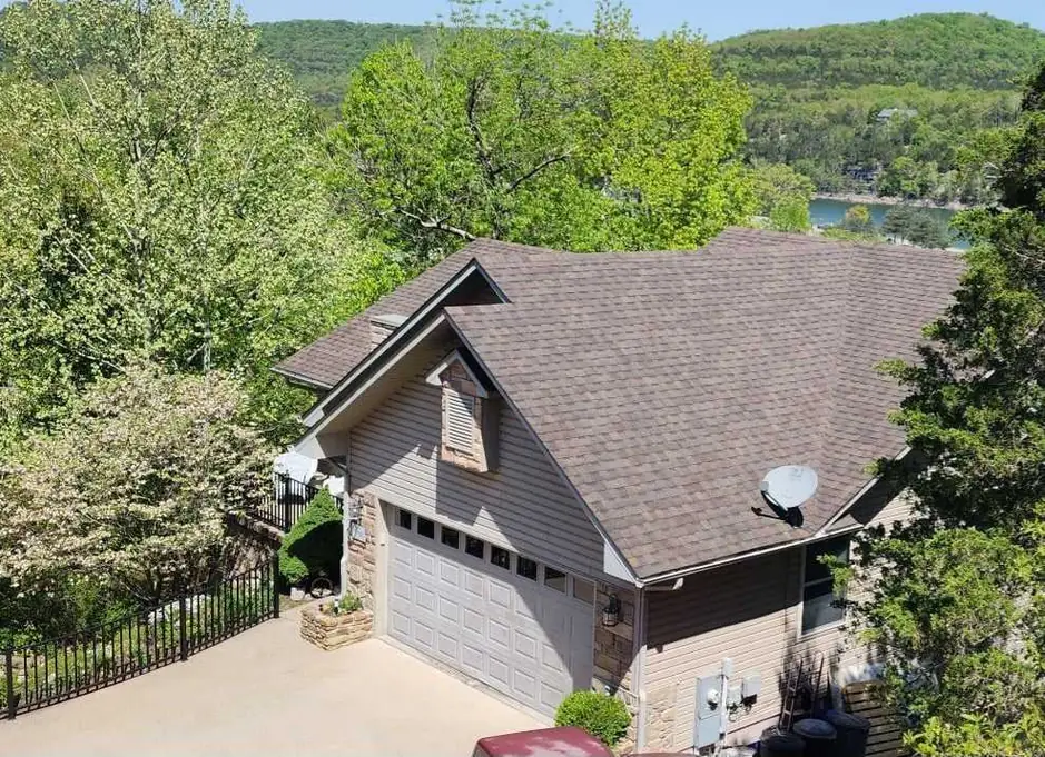 Aerial view of a hillside lake house with a new brown shingle roof